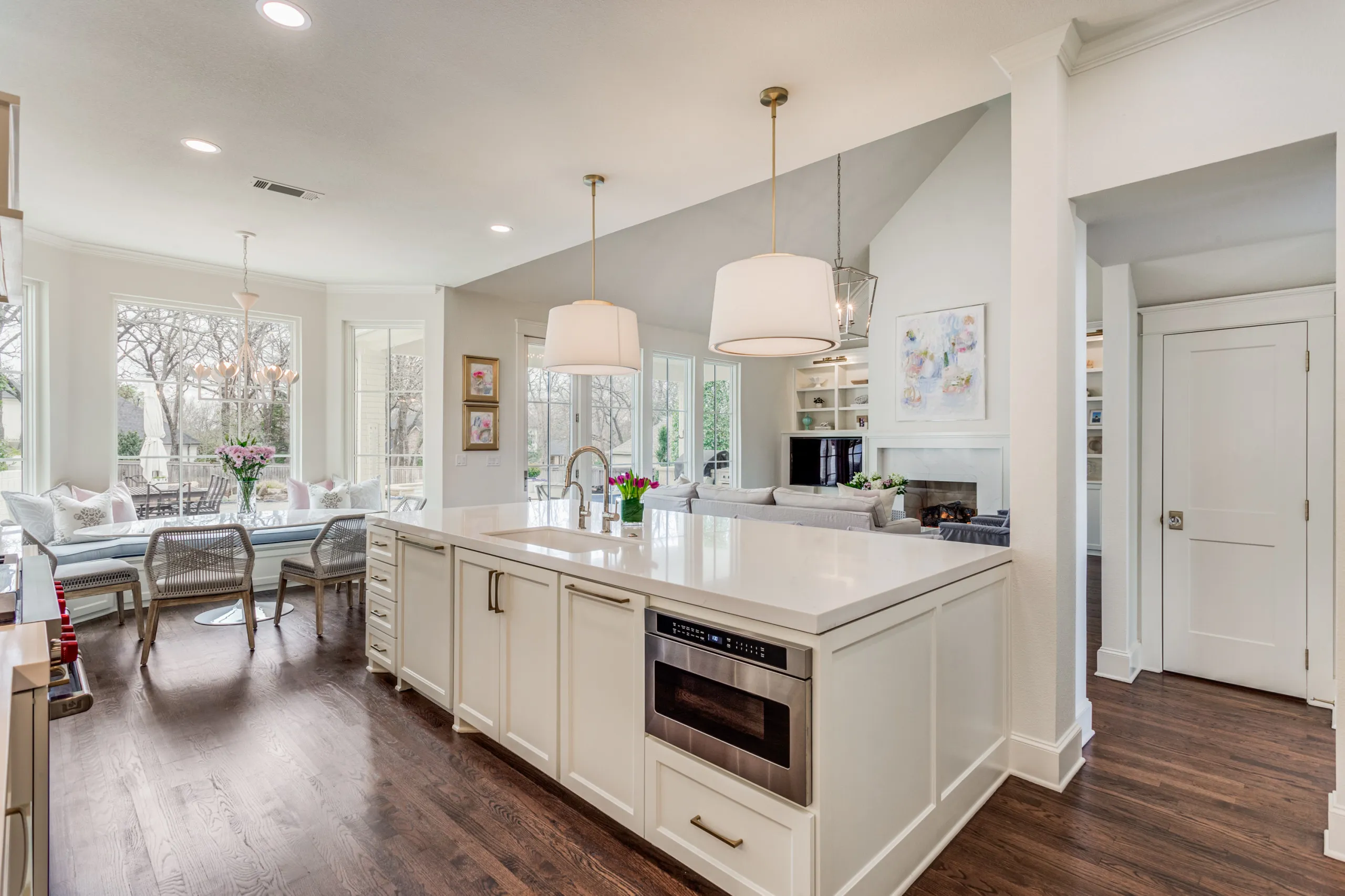 A bright modern-transitional Southlake kitchen with a quartz island, brass fixtures, and layered pendant lighting.