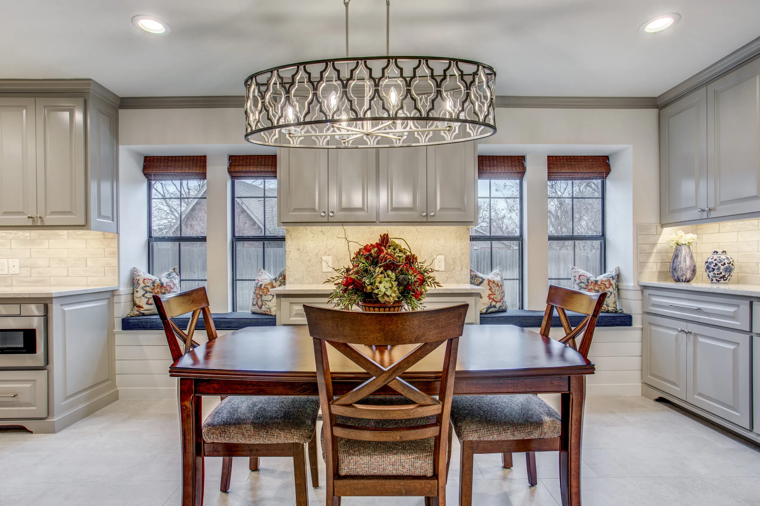 An elegant breakfast area with a statement drum chandelier and built-in window seating.