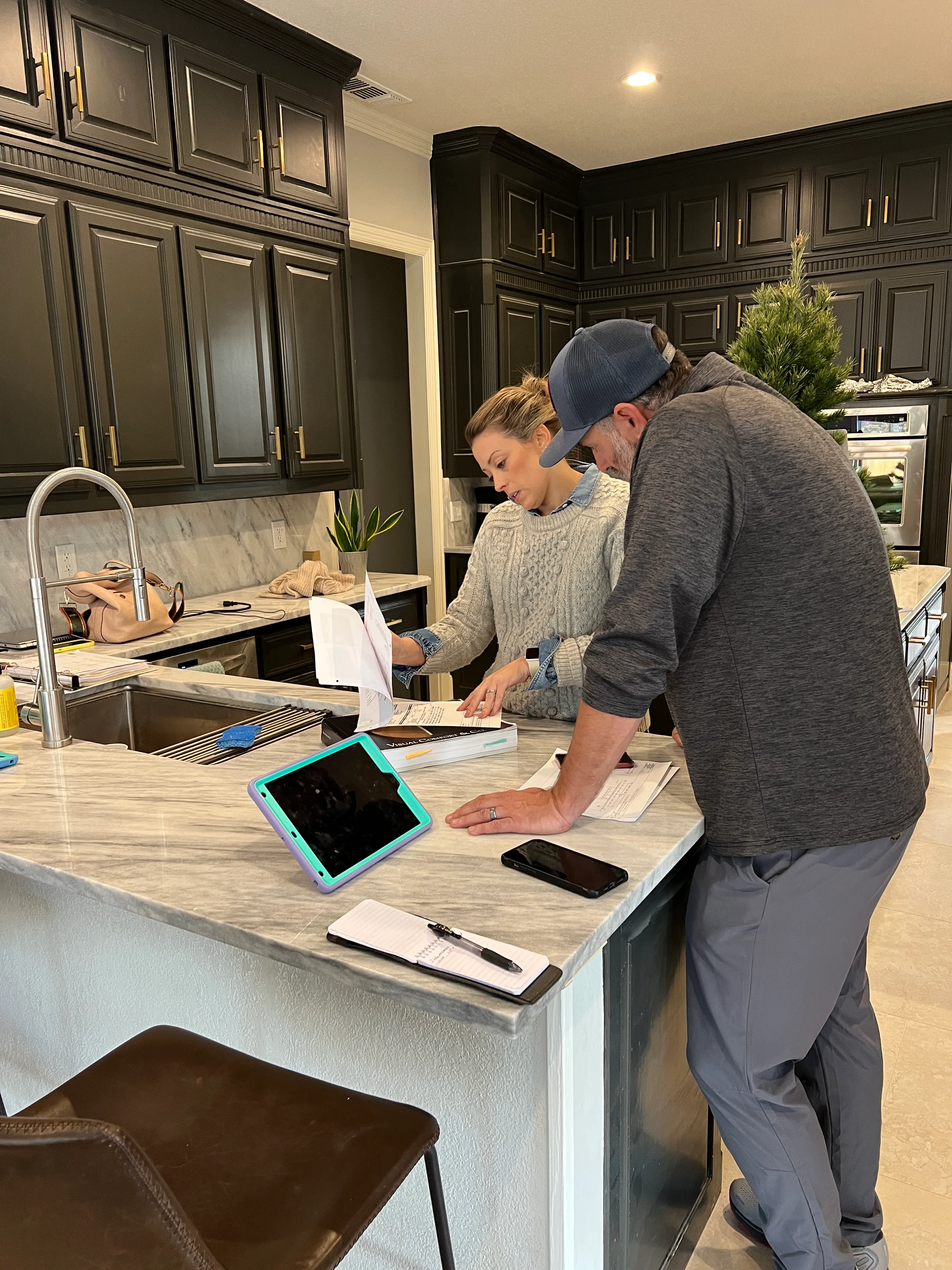 A completed white kitchen and adjacent great room with floor protection drop cloths still in place before final walkthrough.