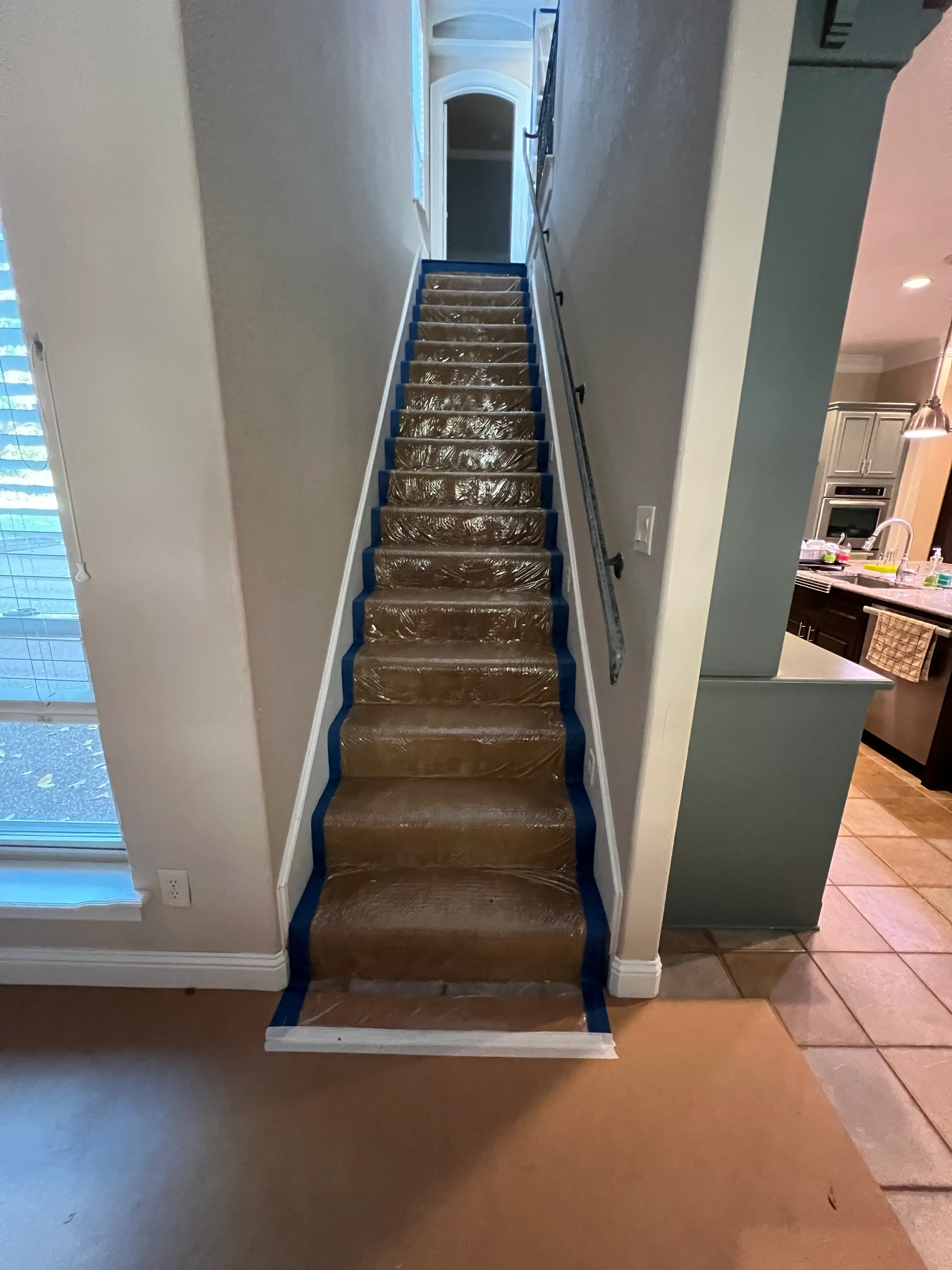 Stair treads wrapped in ram-board and taped along every edge — Swanson's standard protection while construction traffic runs upstairs.
